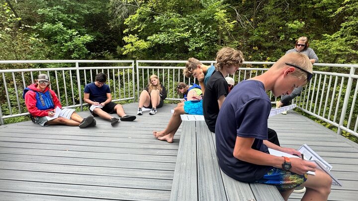 Students writing by the river