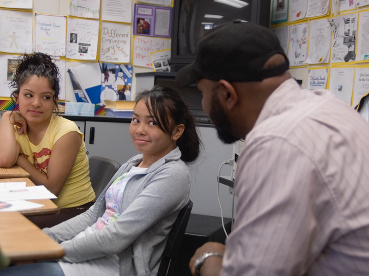 Two students smile at a teacher