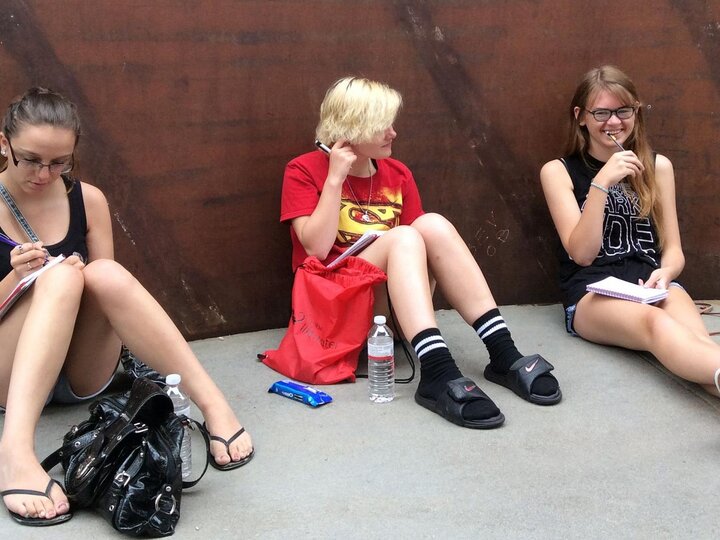 A group of students write inside a sculpture